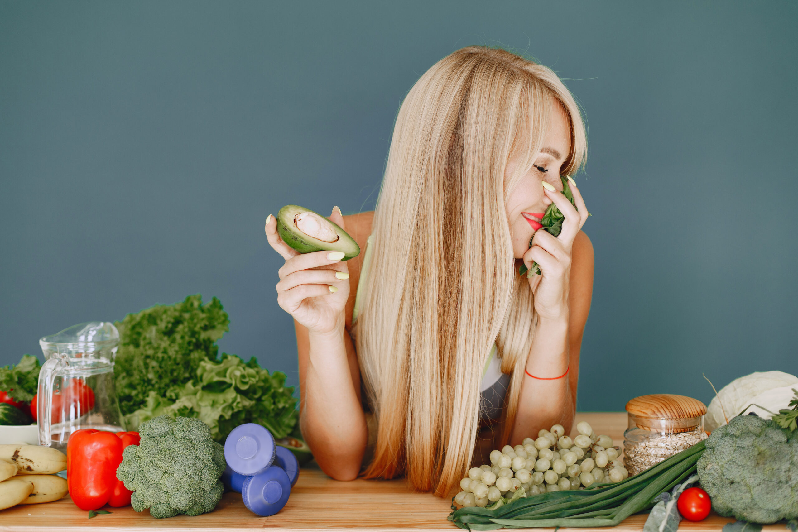 Beautiful girl make a salad. Sporty blonde in a kitchen. Woman with avocado.